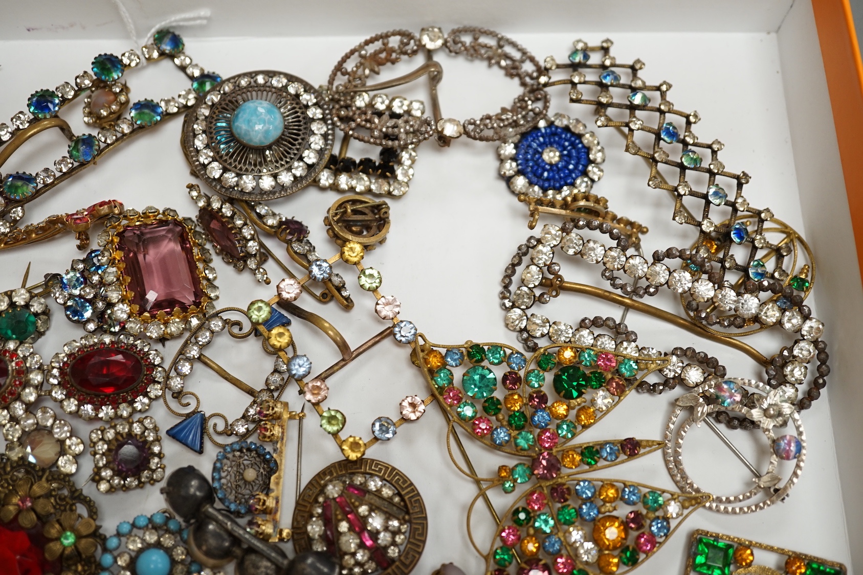 A quantity of assorted coloured and white paste jewellery, including brooches and buckles.